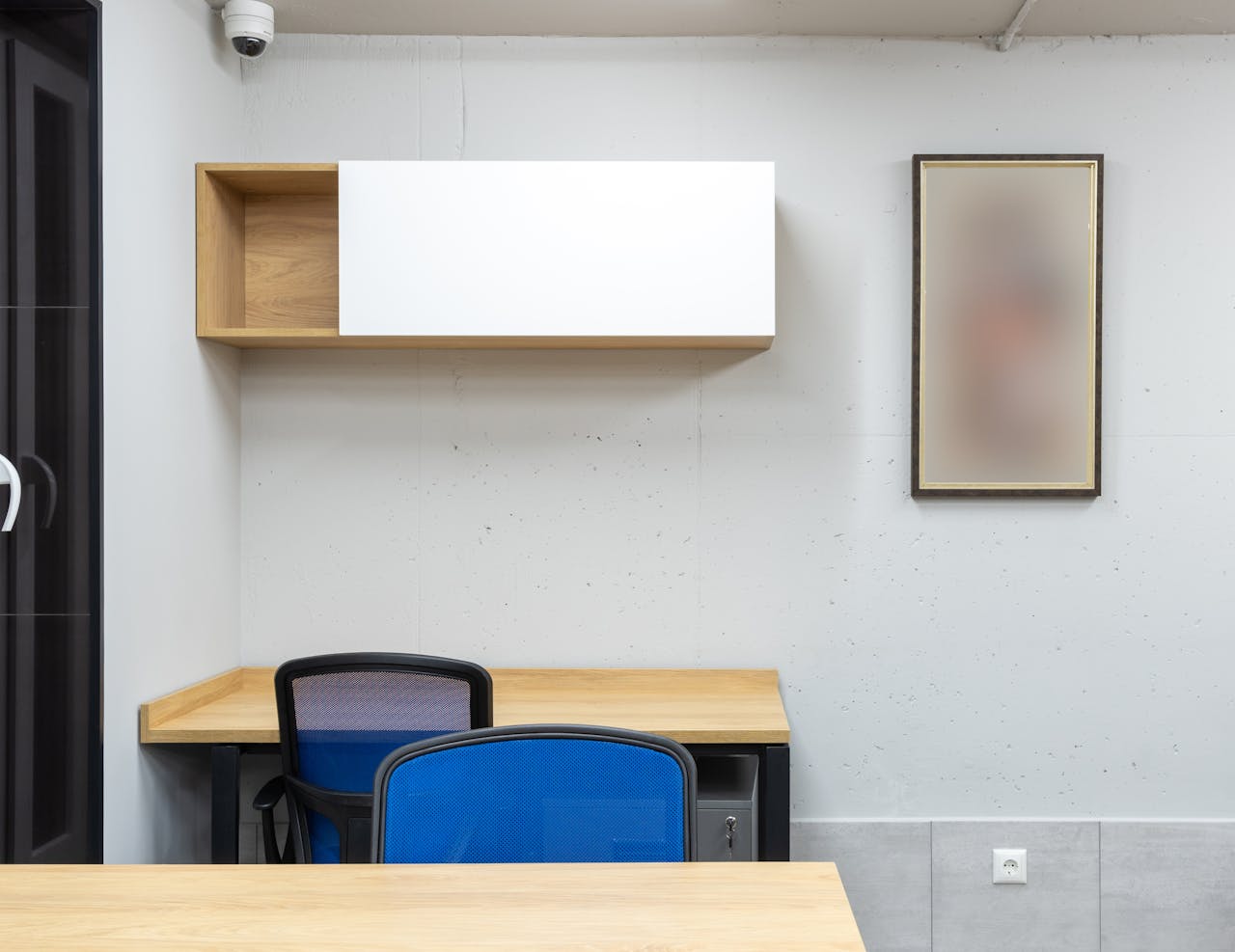 A clean, modern office workspace with blue chairs and wooden shelving for a corporate setting.